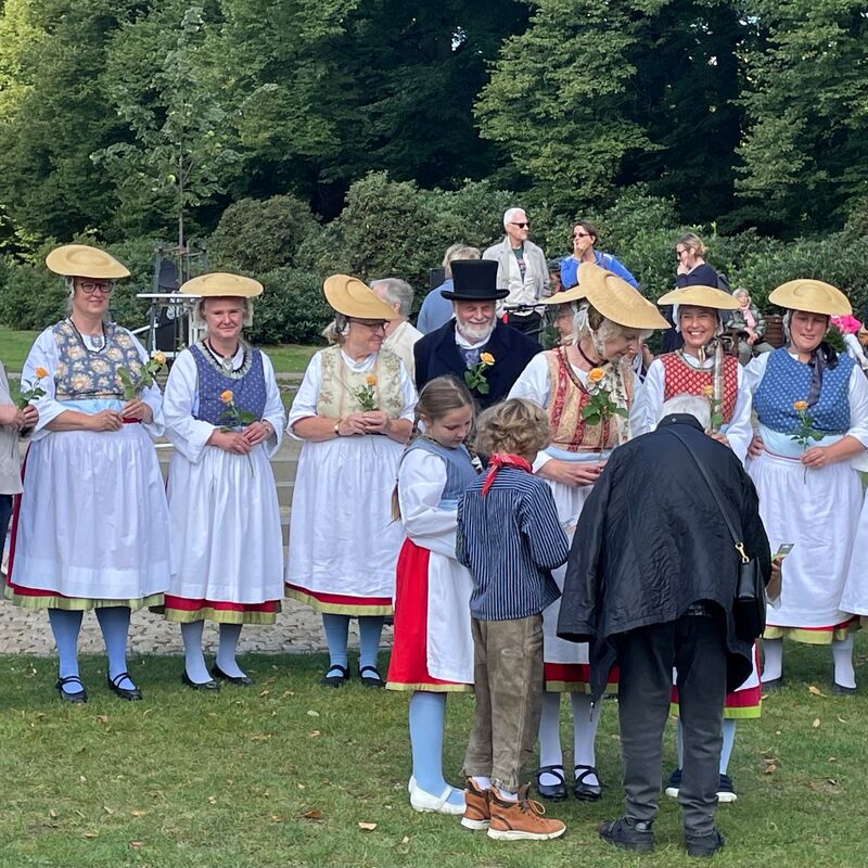 Menschen in traditioneller Tracht versammeln sich in einem Park