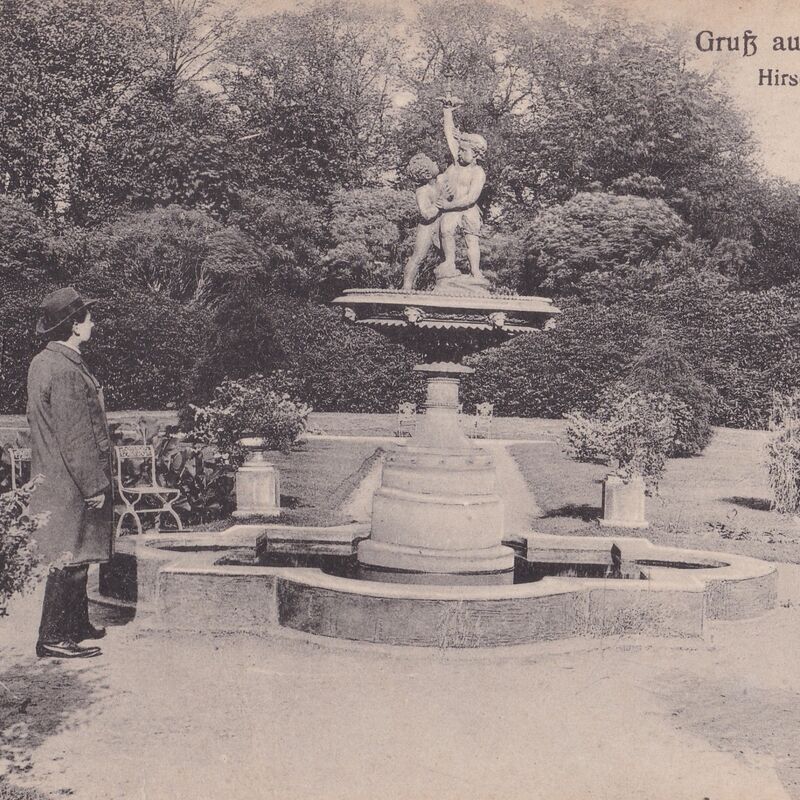 Ein Mann steht in einem Garten, umgeben von Statuen und üppigen Pflanzen